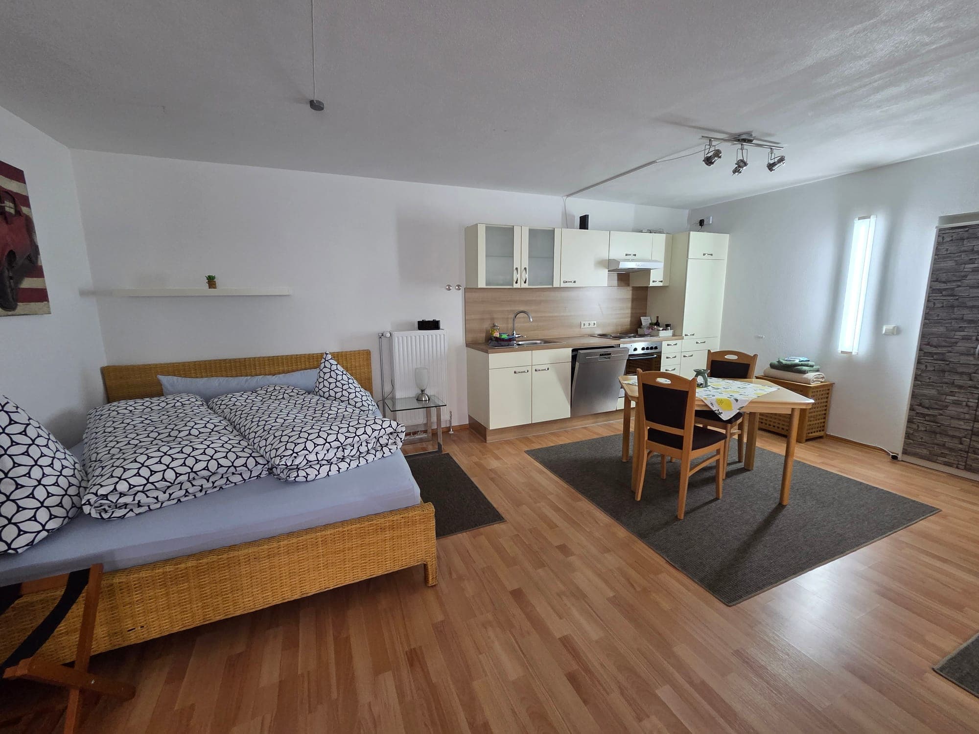 Offener Wohnraum mit Doppelbett, Küchenzeile und Essplatz